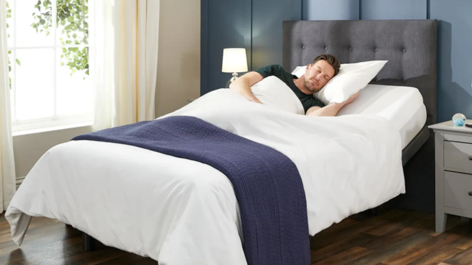 Man sleeping comfortably on an electric adjustable bed with a grey upholstered headboard - Top 5 Adjustable Beds 2026, Solent Mobility Centre Hampshire